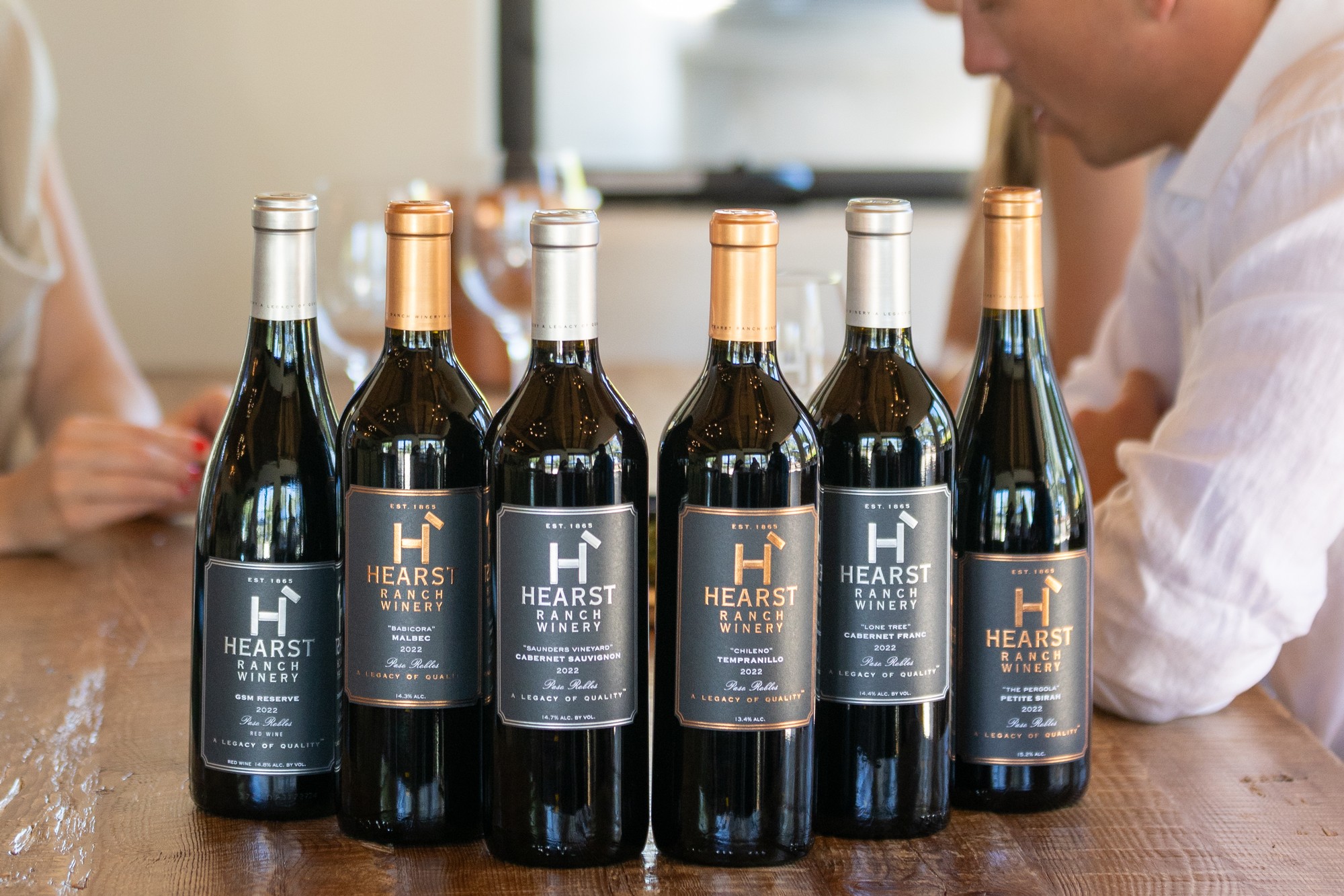 Woman pouring glass of Hearst Ranch Winery red wine.